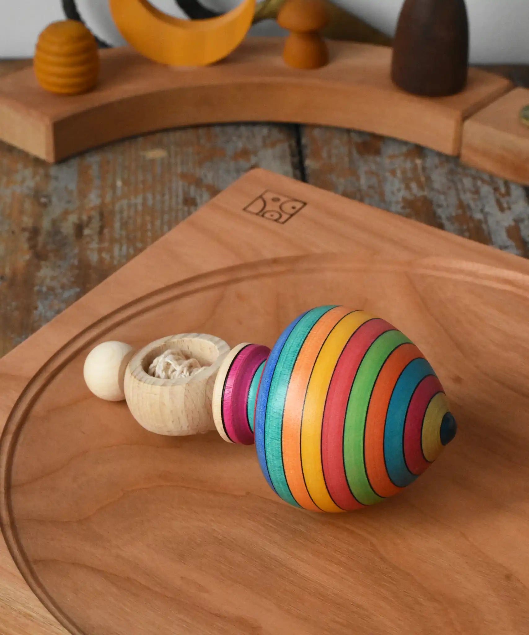 Mader Kreiselmanufaktur ring pull string spinning top placed on a cherry wood spinning plate in the Babipur playroom.