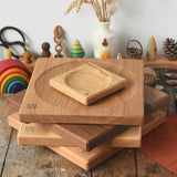 A stack of handmade Mader spinning plates in different woods, cherry, ash, walnut and oak placed on a wooden surface in the Babipur playroom. 