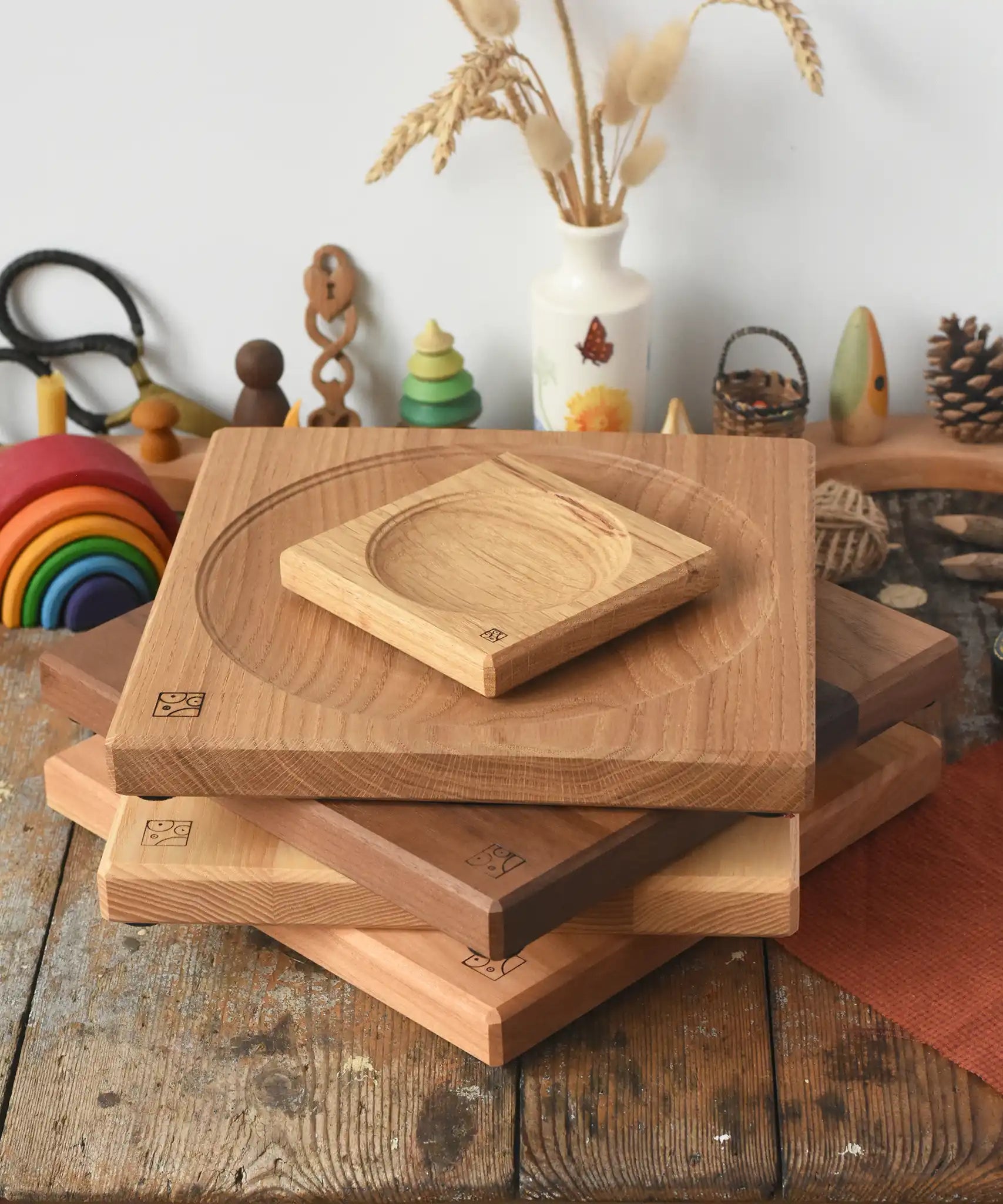 A stack of handmade Mader spinning plates in different woods, cherry, ash, walnut and oak placed on a wooden surface in the Babipur playroom. 