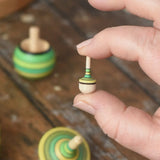 Miniature spinner from the Mader Kreiselmanufaktur green grass spinning top learning set in an adult's hand in the Babipur playroom. 