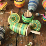 Mader Kreiselmanufaktur green grass spinning top learning set placed on a wooden surface in the Babipur playroom. Other colour variations of the same set can be seen in the background.