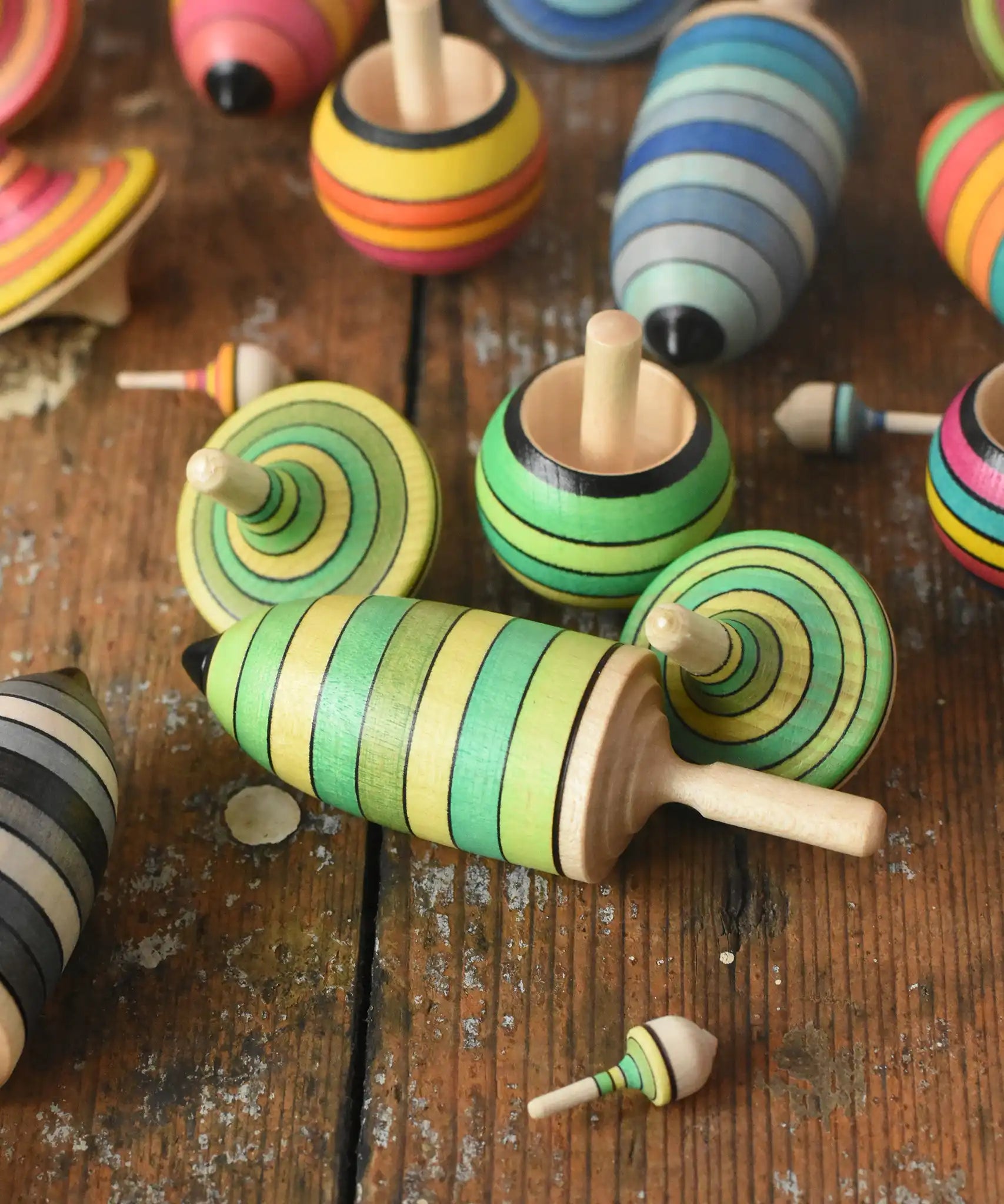 Mader Kreiselmanufaktur green grass spinning top learning set placed on a wooden surface in the Babipur playroom. Other colour variations of the same set can be seen in the background.