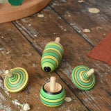 Mader Kreiselmanufaktur green grass spinning top learning set placed on a wooden surface in the Babipur playroom. 