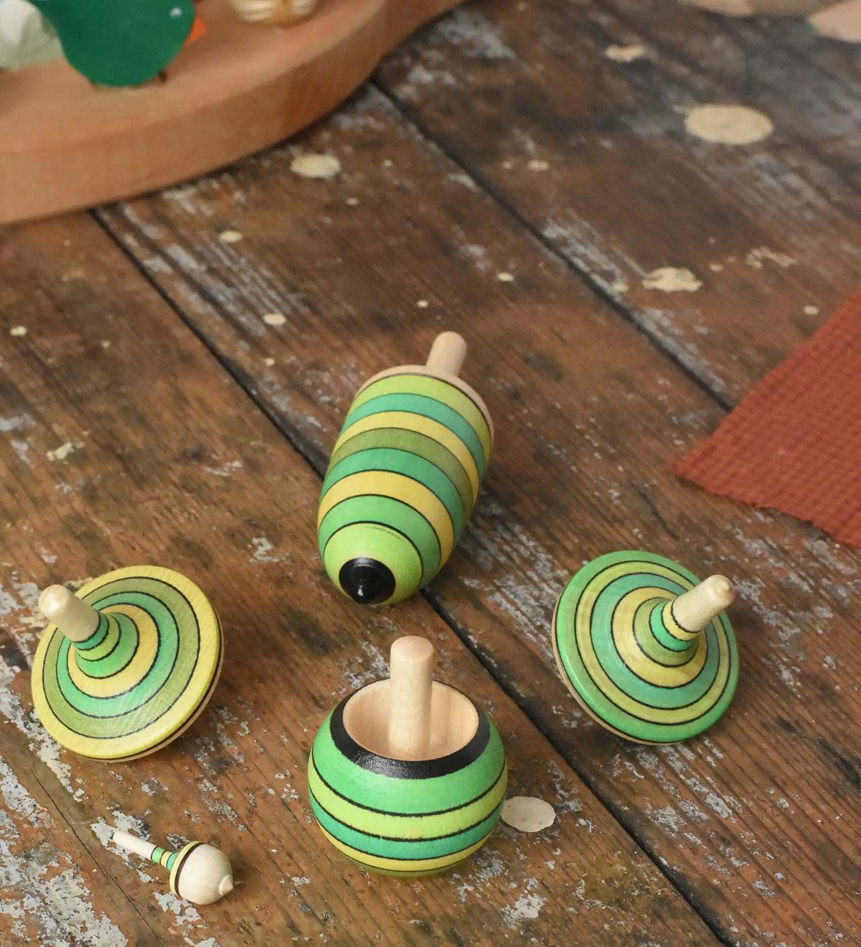 Mader Kreiselmanufaktur green grass spinning top learning set placed on a wooden surface in the Babipur playroom. 