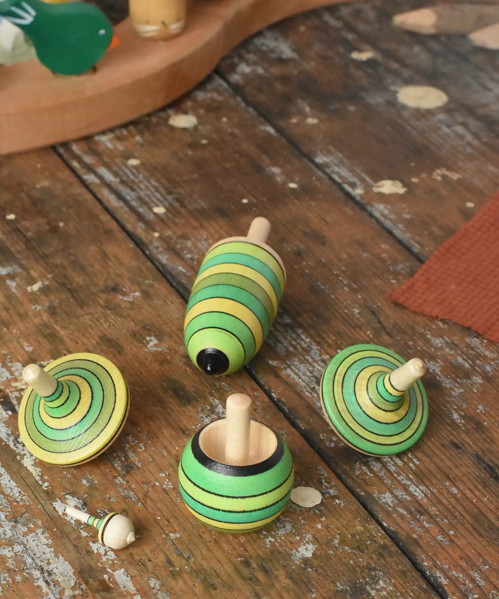 Mader Kreiselmanufaktur green grass spinning top learning set placed on a wooden surface in the Babipur playroom. 