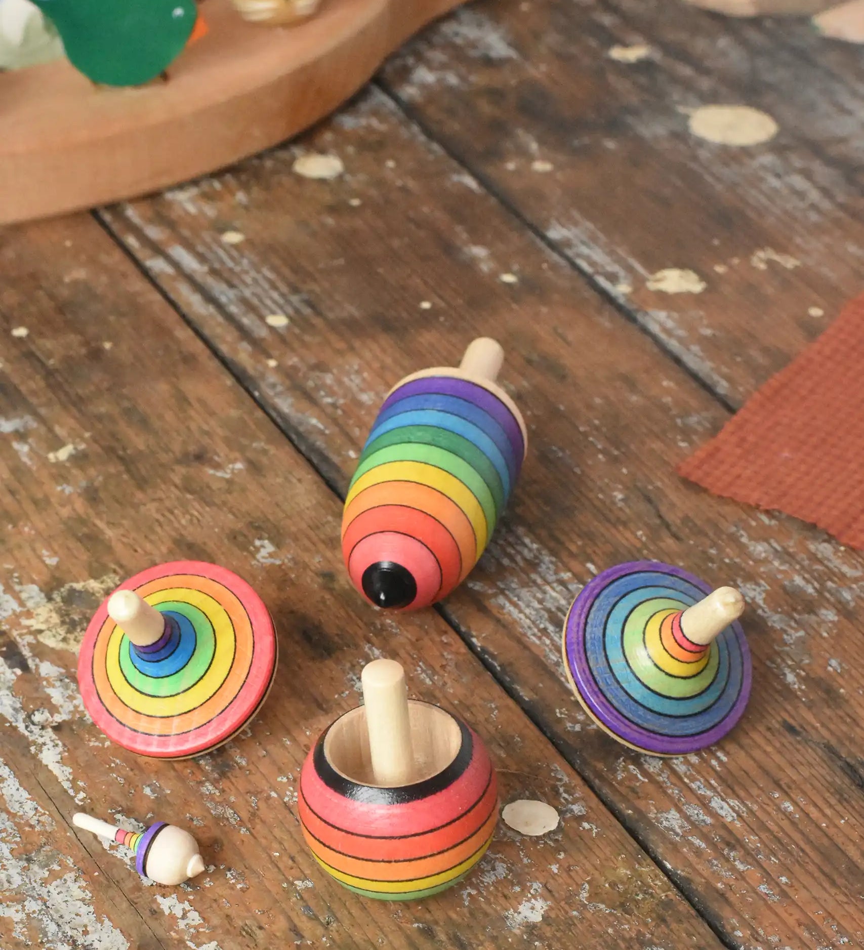 Mader Kreiselmanufaktur rainbow spinning top learning set placed on a wooden surface in the Babipur playroom. 