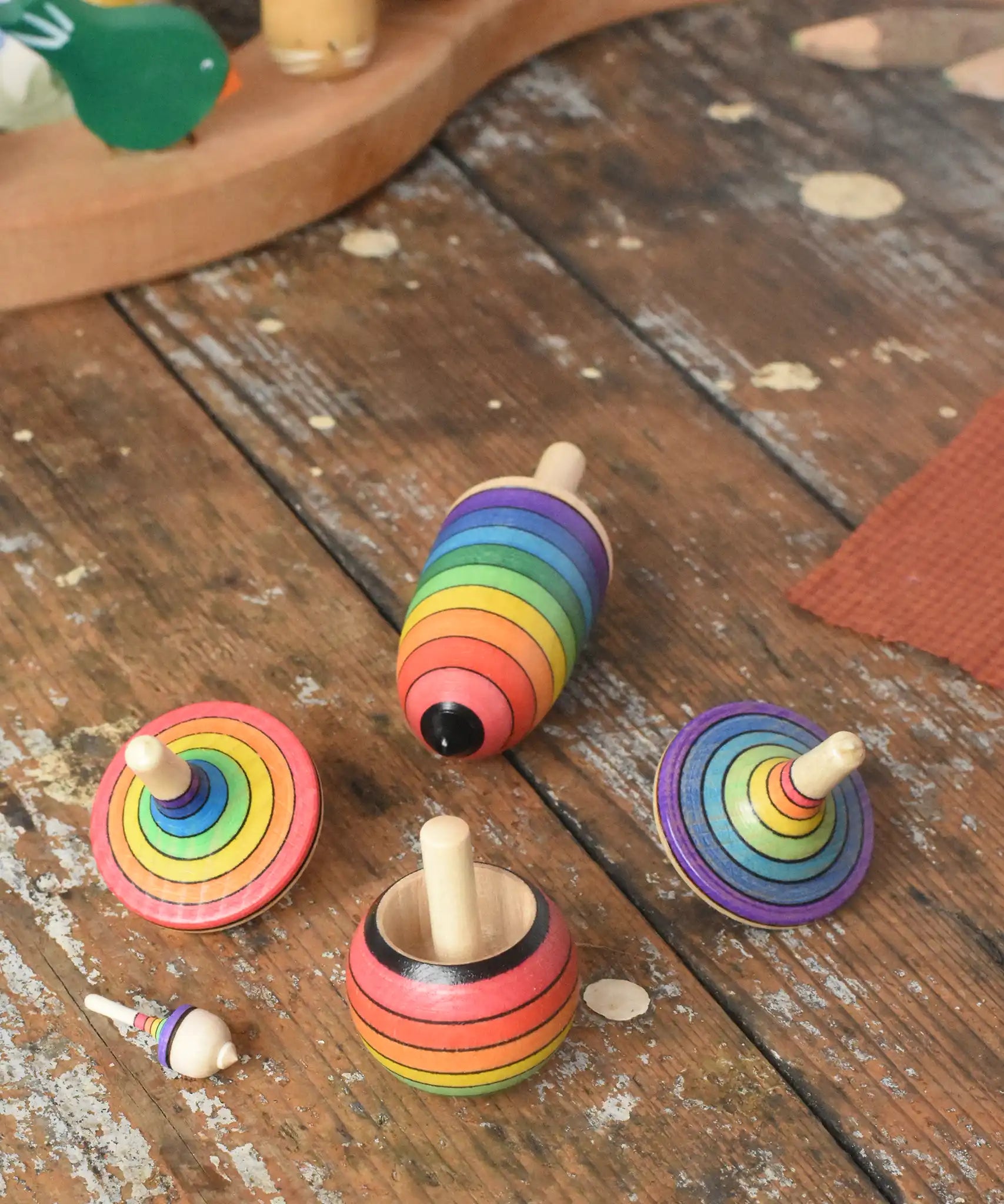Mader Kreiselmanufaktur rainbow spinning top learning set placed on a wooden surface in the Babipur playroom. 