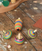 Mader Kreiselmanufaktur striped spinning top learning set placed on a wooden surface in the Babipur playroom. 