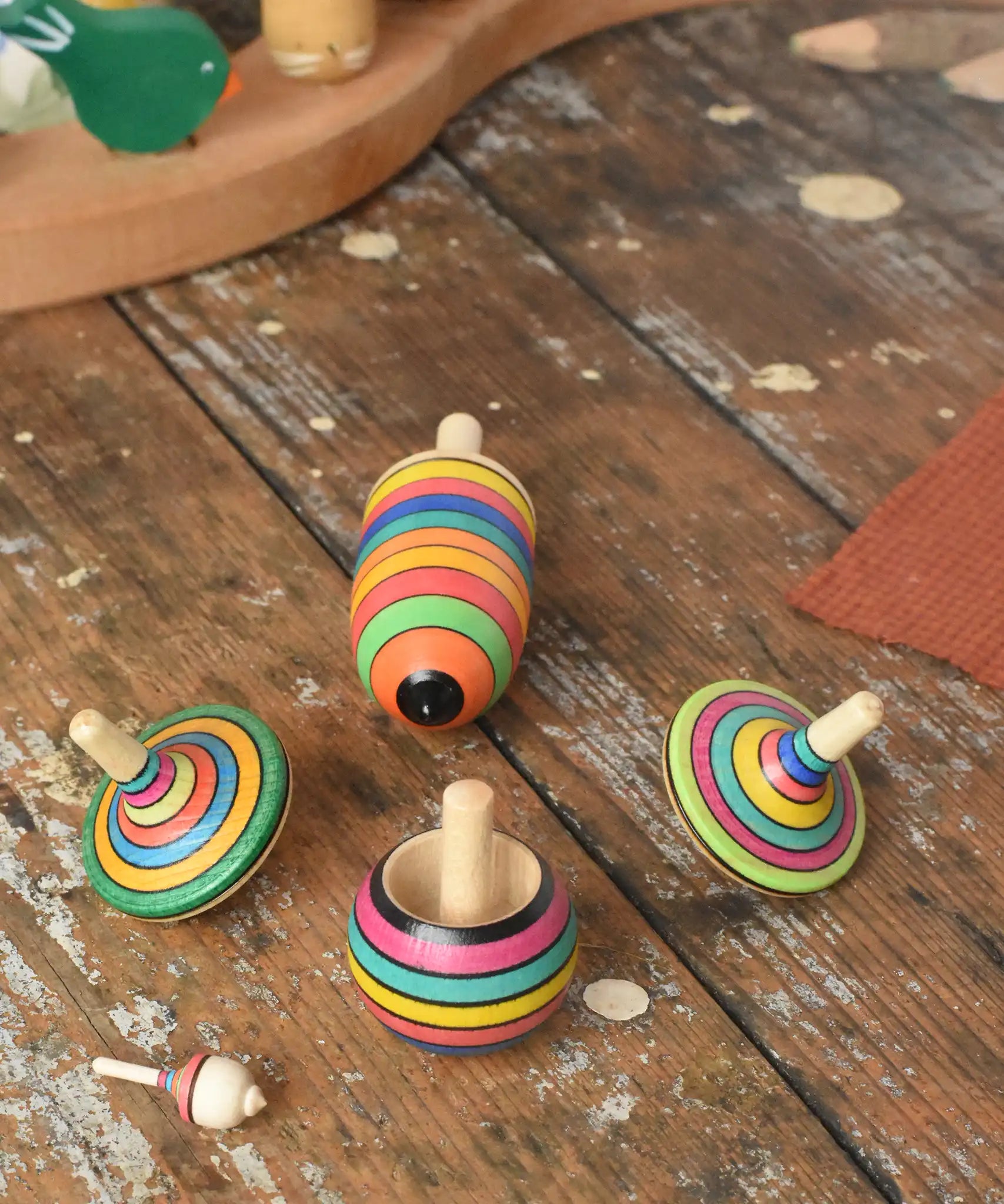 Mader Kreiselmanufaktur striped spinning top learning set placed on a wooden surface in the Babipur playroom. 