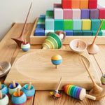 Mader wooden spinning top collection laid out next to a Mader spinning plate and a Grimms Large Stepped Pyramid