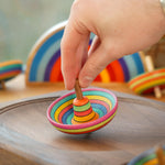 Close up of a hand holding a mader plastic free wooden sombrero spinning top on a mader spinning plate