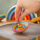 Close up of a hand holding a mader plastic free wooden sombrero spinning top on a mader spinning plate