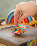 Close up of a hand holding a mader plastic free wooden sombrero spinning top on a mader spinning plate