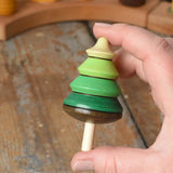 Mader Kreiselmanufaktur green tree spinning top in an adult's hand in the Babipur playroom.