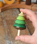 Mader Kreiselmanufaktur green tree spinning top in an adult's hand in the Babipur playroom.
