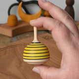Mader bee spinning top shown in an adult's hand in the Babipur playroom. 