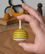 Mader bee spinning top shown in an adult's hand in the Babipur playroom. 