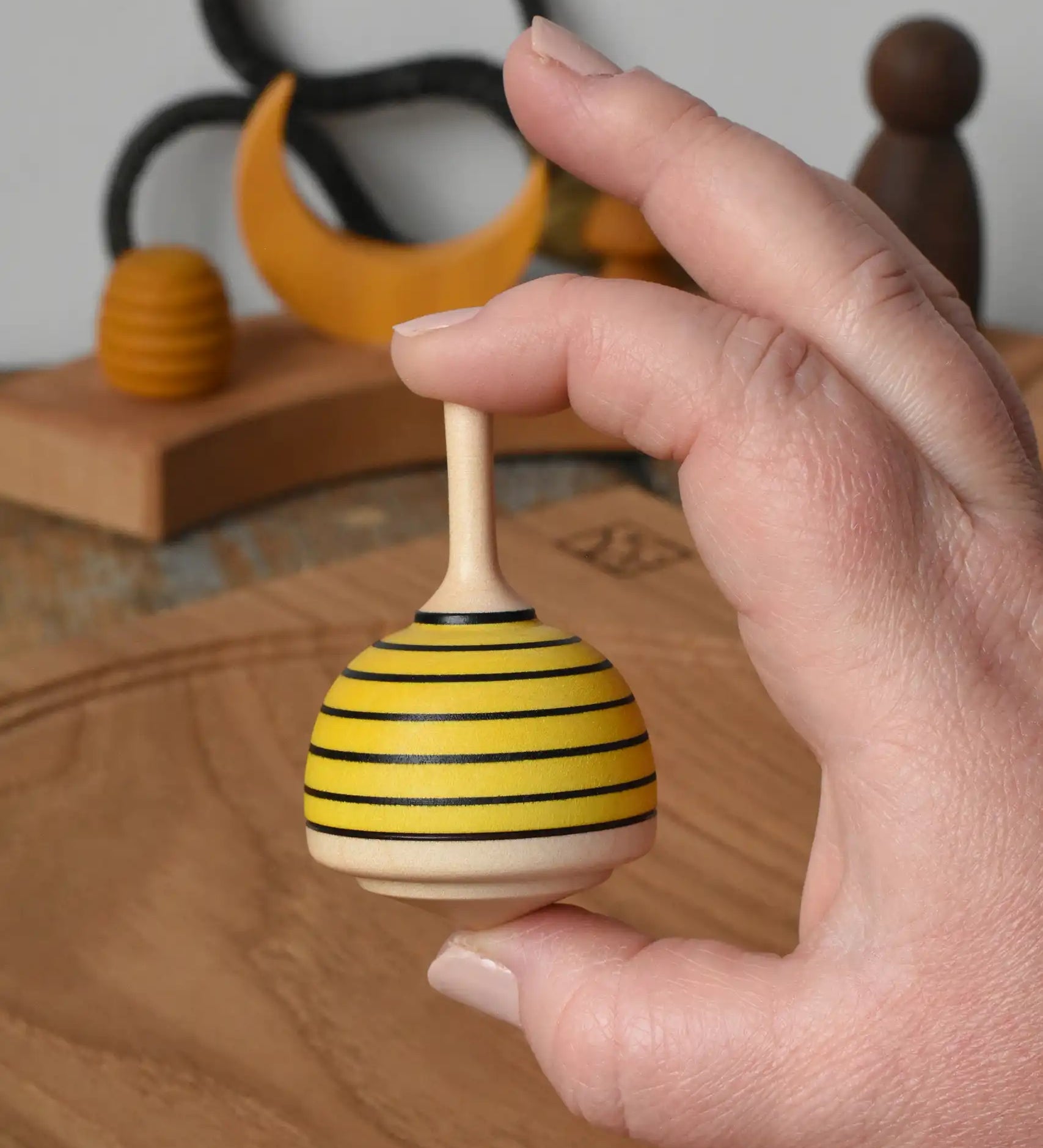 Mader bee spinning top shown in an adult's hand in the Babipur playroom. 