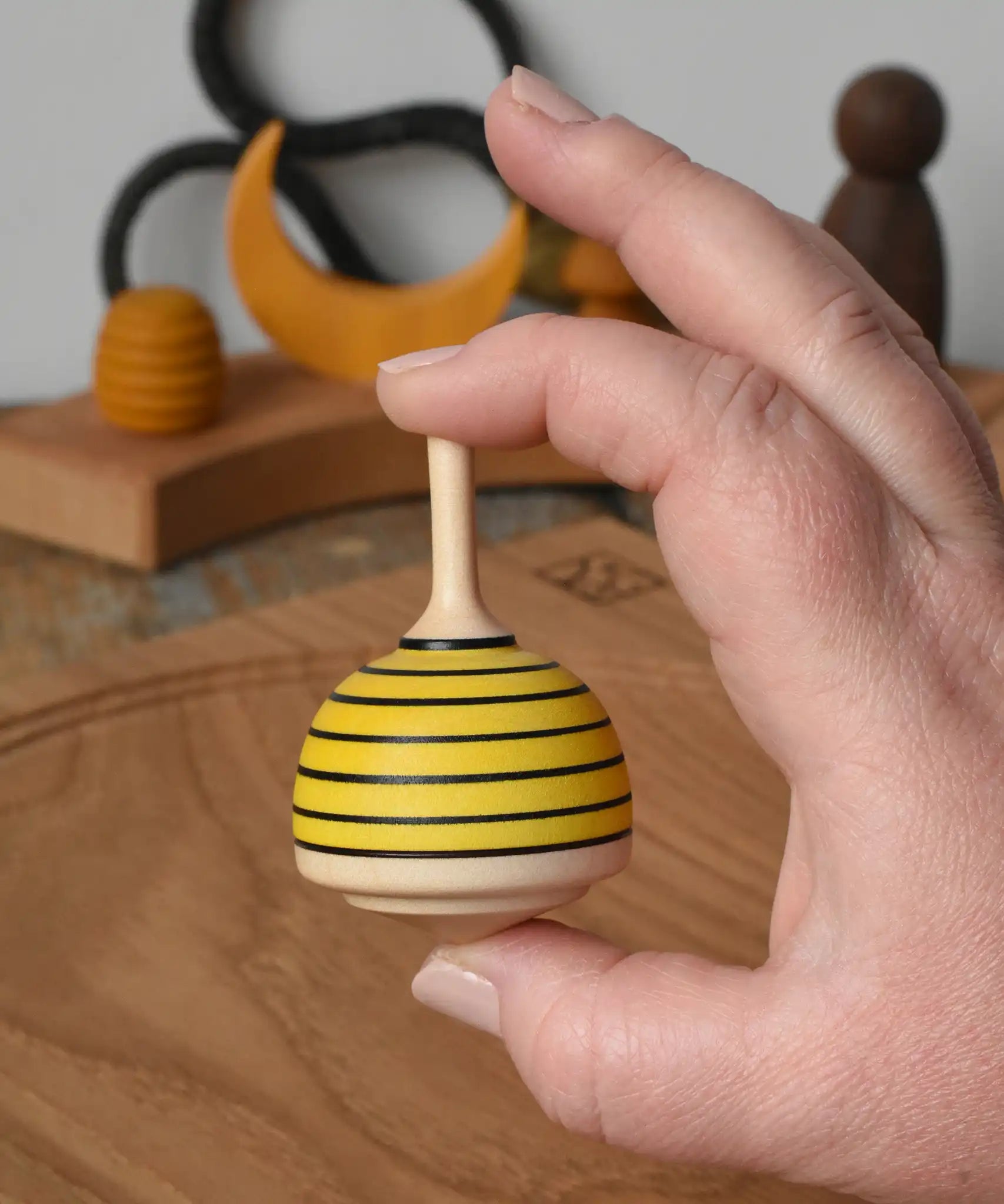 Mader bee spinning top shown in an adult's hand in the Babipur playroom. 