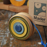 Mader Kreiselmanufaktur yoyo harlequin placed on a wooden desk in the Babipur playroom. The cardboard packaging box can be seen in the background.