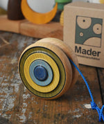 Mader Kreiselmanufaktur yoyo harlequin placed on a wooden desk in the Babipur playroom. The cardboard packaging box can be seen in the background.