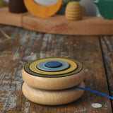 Mader Kreiselmanufaktur yoyo harlequin placed on it's side on a wooden desk in the Babipur playroom.
