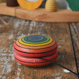 Mader yoyo rainbow placed on it's side on a wooden desk in the Babipur playroom.