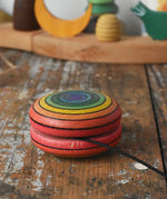 Mader yoyo rainbow placed on it's side on a wooden desk in the Babipur playroom.