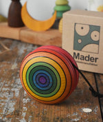 Mader yoyo rainbow placed on a wooden desk in the Babipur playroom. Cardboard packaging box can be seen in the background.