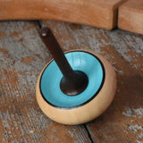 Mader Zwirbel Spinning Top in blue placed on a wooden desk in the Babipur playroom.