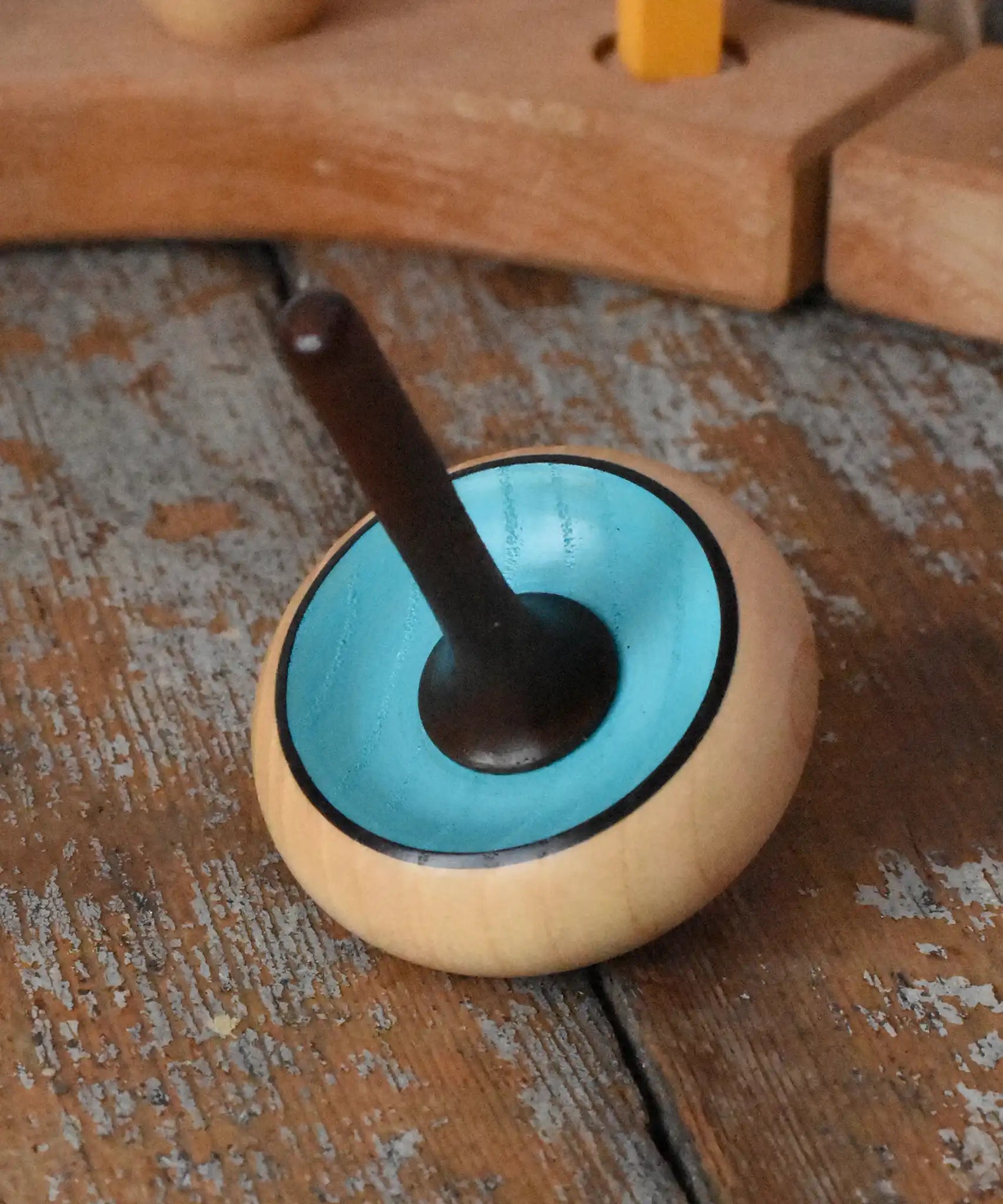 Mader Zwirbel Spinning Top in blue placed on a wooden desk in the Babipur playroom.