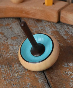 Mader Zwirbel Spinning Top in blue placed on a wooden desk in the Babipur playroom.
