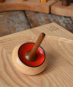 Mader Zwirbel Spinning Top in red placed on an an ash spinning board  in the Babipur playroom.