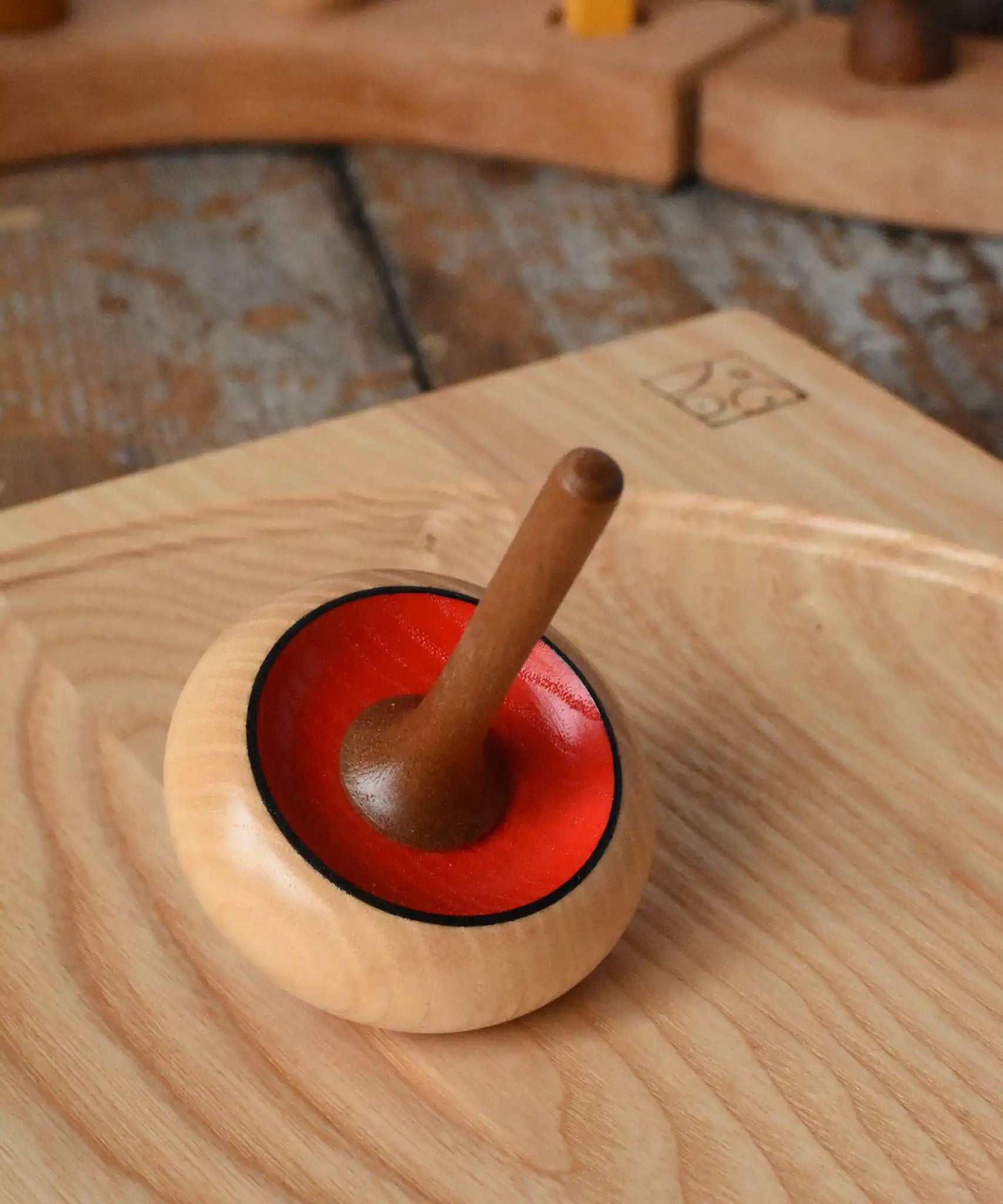 Mader Zwirbel Spinning Top in red placed on an an ash spinning board  in the Babipur playroom.