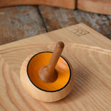Mader Zwirbel Spinning Top in yellow placed on an an ash spinning board  in the Babipur playroom.