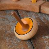 Mader Zwirbel Spinning Top in yellow placed on a wooden desk in the Babipur playroom.