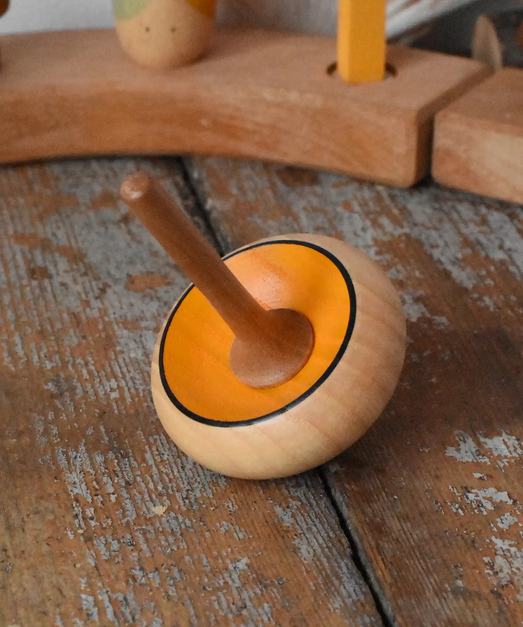 Mader Zwirbel Spinning Top in yellow placed on a wooden desk in the Babipur playroom.