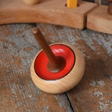 Mader Zwirbel Spinning Top in red placed on a wooden desk in the Babipur playroom.