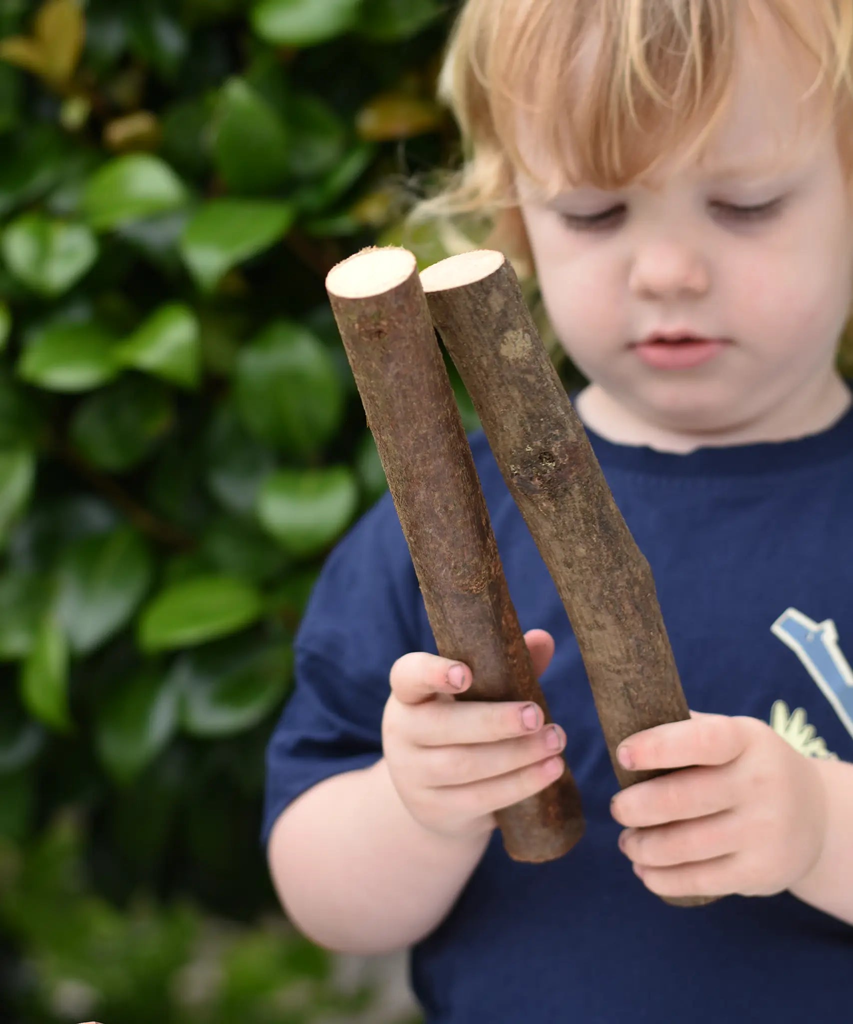 Child holding two long log pieces from the Magic Wood Eco Blocks Big Box 70 piece set.