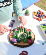 Child making a mandala on a large log slice from the Magic Wood Eco Blocks Big Box 70 piece set.