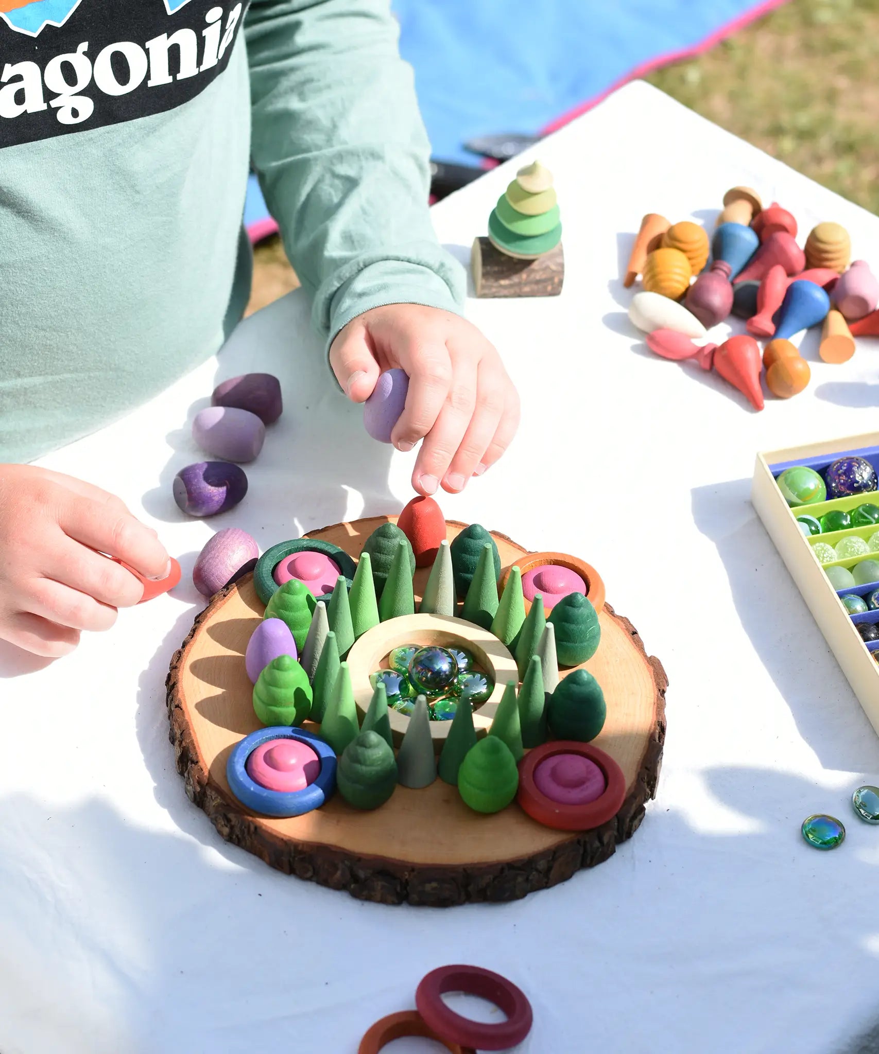 Child making a mandala on a large log slice from the Magic Wood Eco Blocks Big Box 70 piece set.