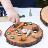 Child placing flat glass marbles and Grapat mandala pieces on a large log slice from the Magic Wood Eco Blocks Big Box 70 piece set.