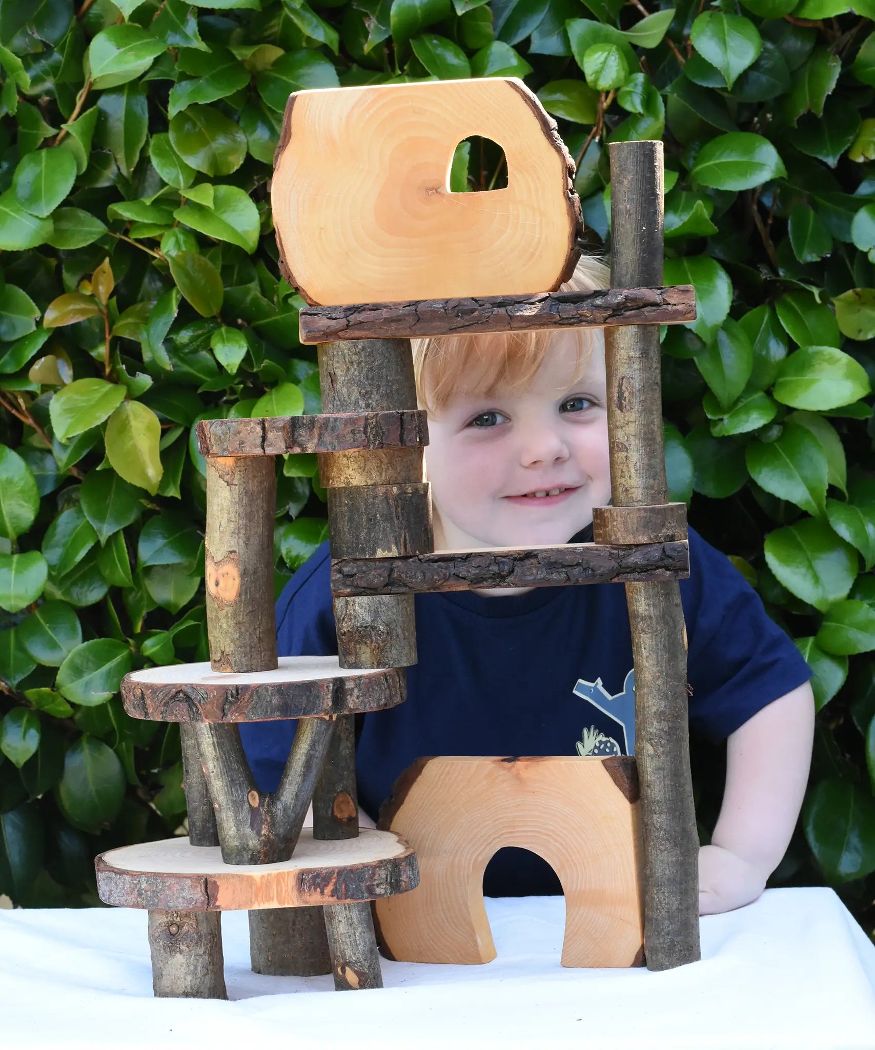 Build created using the Magic Wood Eco Blocks in a 22 piece set. Child peeping through smiling.