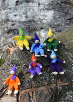 Magic Wood Six Felt Elves shown in seated positions on a log outdoors.