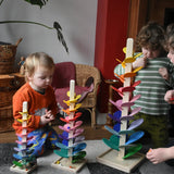 Children sitting around mini, small and large Magic Wood marble trees, placing marbles on the rainbow coloured leaves.