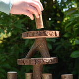 Child's hand placing a tall log piece on the top of a structure created using the Magic Wood oiled ecoBlocks 36 piece set.