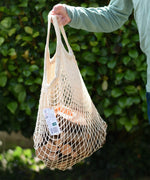 Child holding the  Magic Wood wooden oiled ecoBlocks 36 piece set in it's net storage bag.