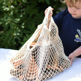 Child lifting the net bag containing Magic Wood oiled ecoBlocks in a 36 piece set.