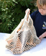Child lifting the net bag containing Magic Wood oiled ecoBlocks in a 36 piece set.
