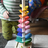 The small Magic Wood rainbow marble tree with glass marble cascading down the wooden leaves. A child kneeling behind.